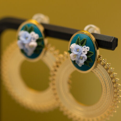 Handmodellierte Ohrringe im Boho-Stil. Petrolfarbene Blüteninsel mit weißen und hellblauen Blüten, kunstvoll modelliert und in eine Edelstahlfassung im Boho-Stil eingefasst.