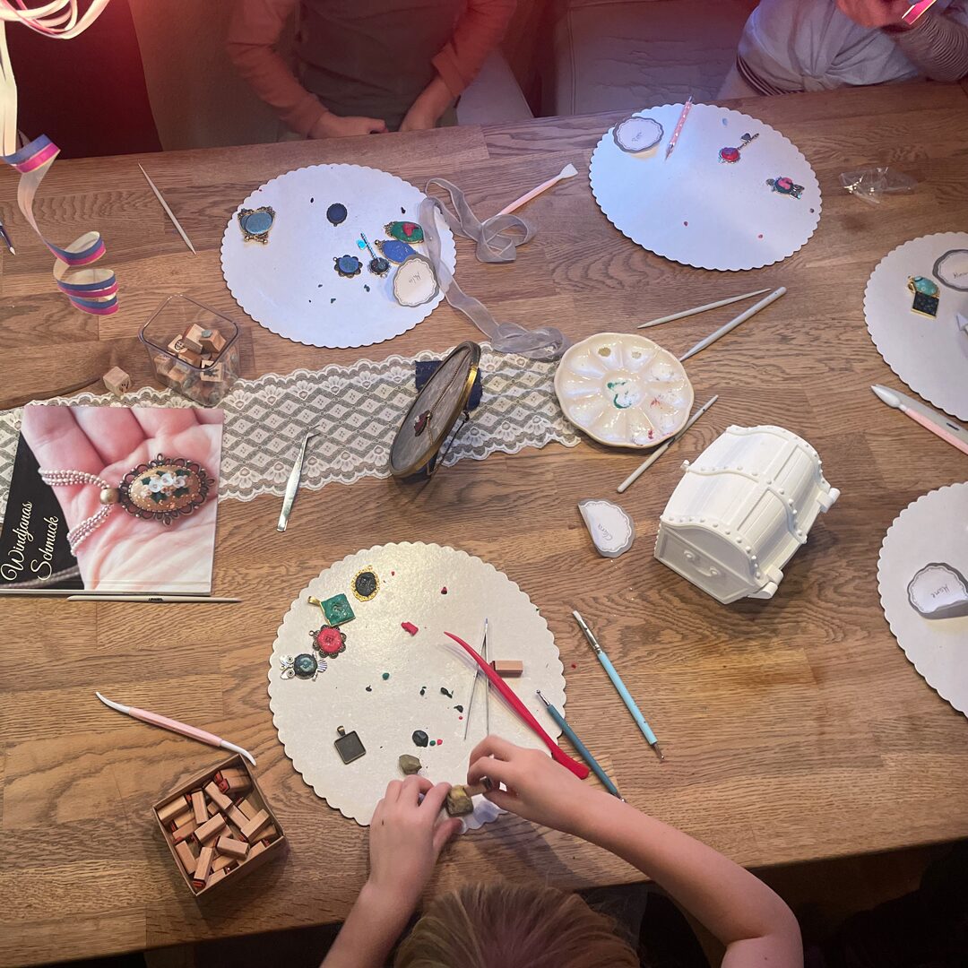 Kinder arbeiten gemeinsam an ihren Schmuck-Anhängern