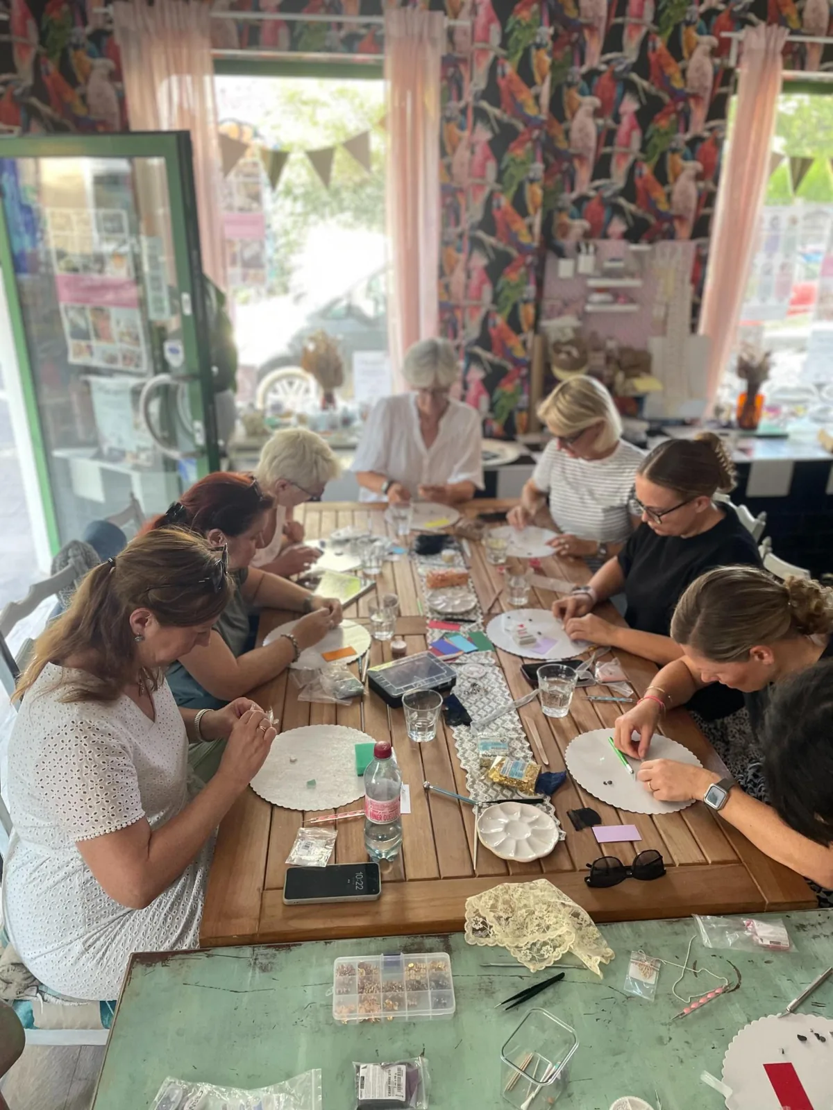 Teilnehmerinnen gestalten gemeinsam Schmuck an einem großen Arbeitstisch im Stilwald Atelier